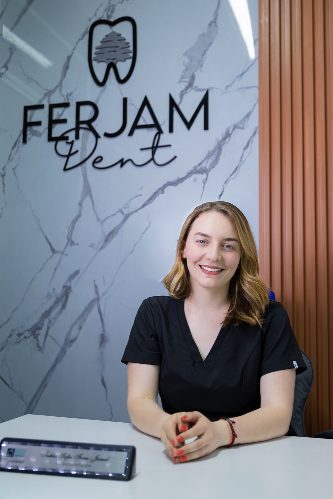 Dra. Teshba Sofía en la recepción de FerJam Dent, frente al logotipo de la clínica